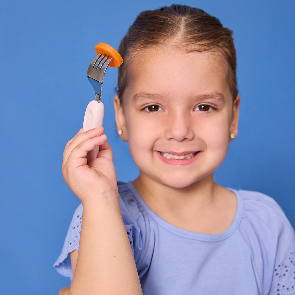 Young girl holding a fork with a carrot on a blue background