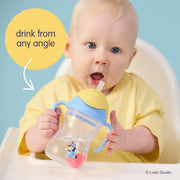 Baby holding a Bluey sippy cup with a blue handle against a light blue background.