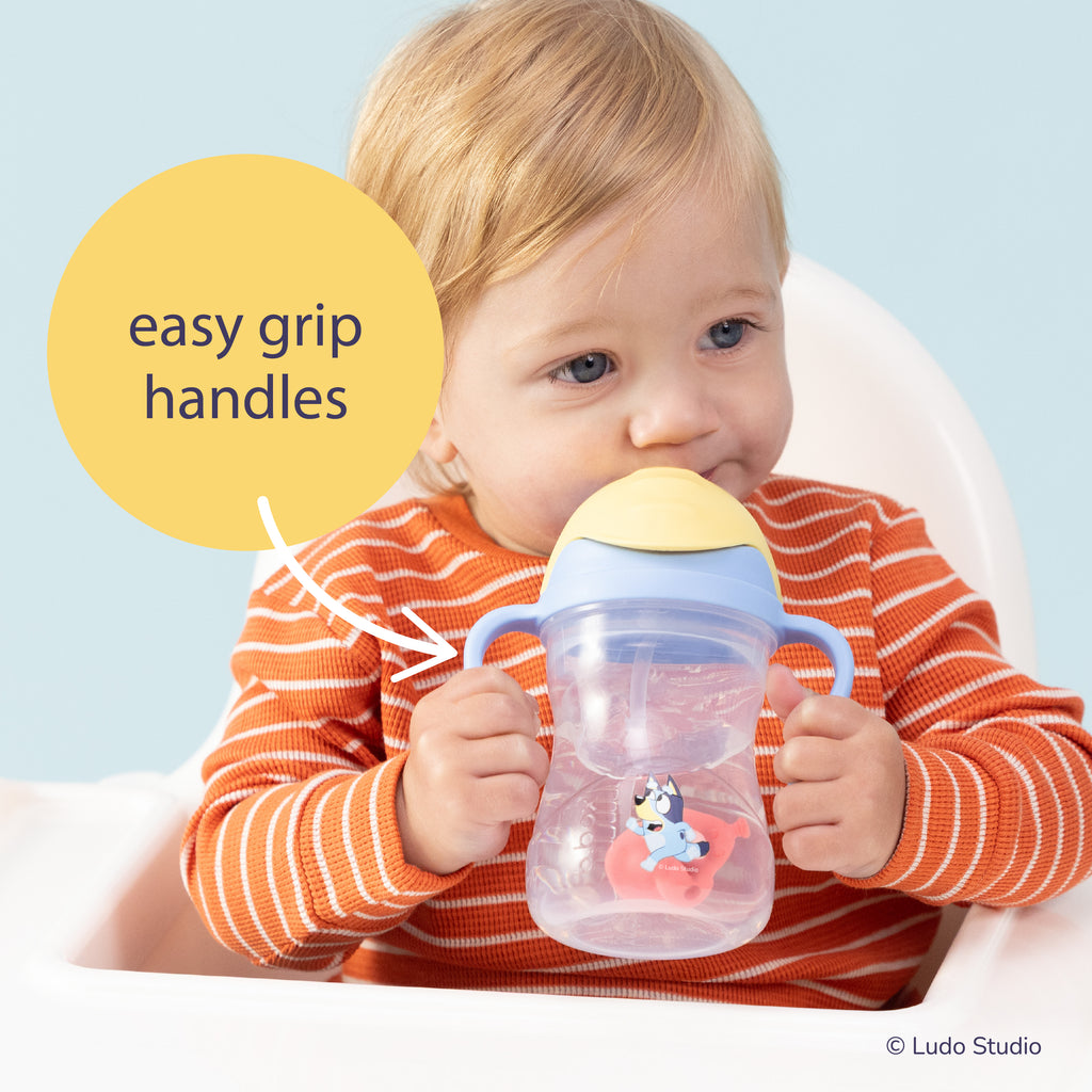 Child holding a Bluey sippy cup with 'easy grip handles' text and Ludo Studio logo.