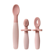 Set of pink baby feeding utensils on a white background